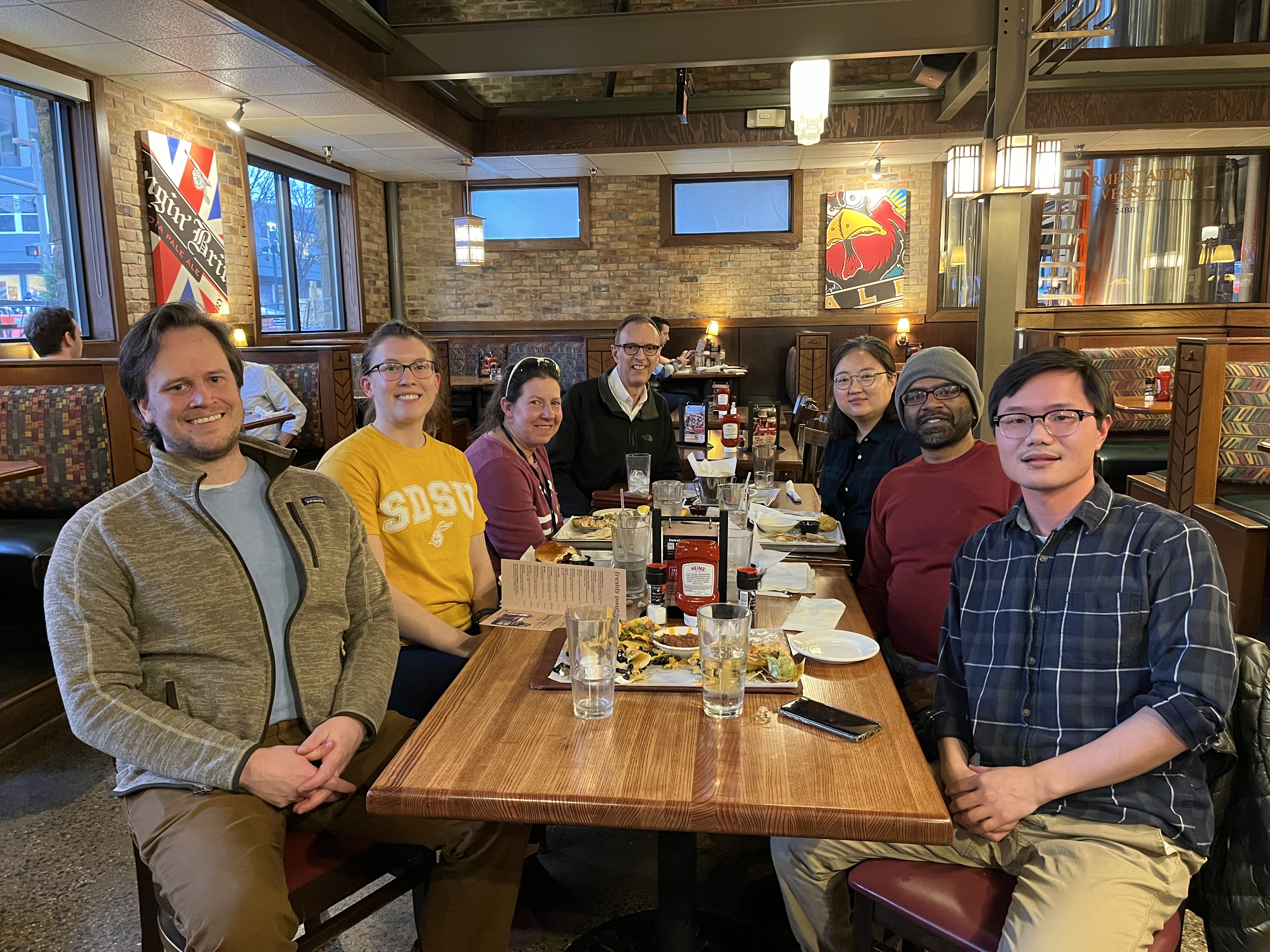 Lab members seated around two wooden tables at a restaurant in 2023 during a lunch. 