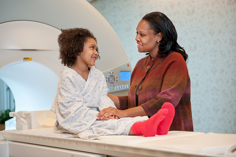 Parent reassuring child on table in front of scanner.