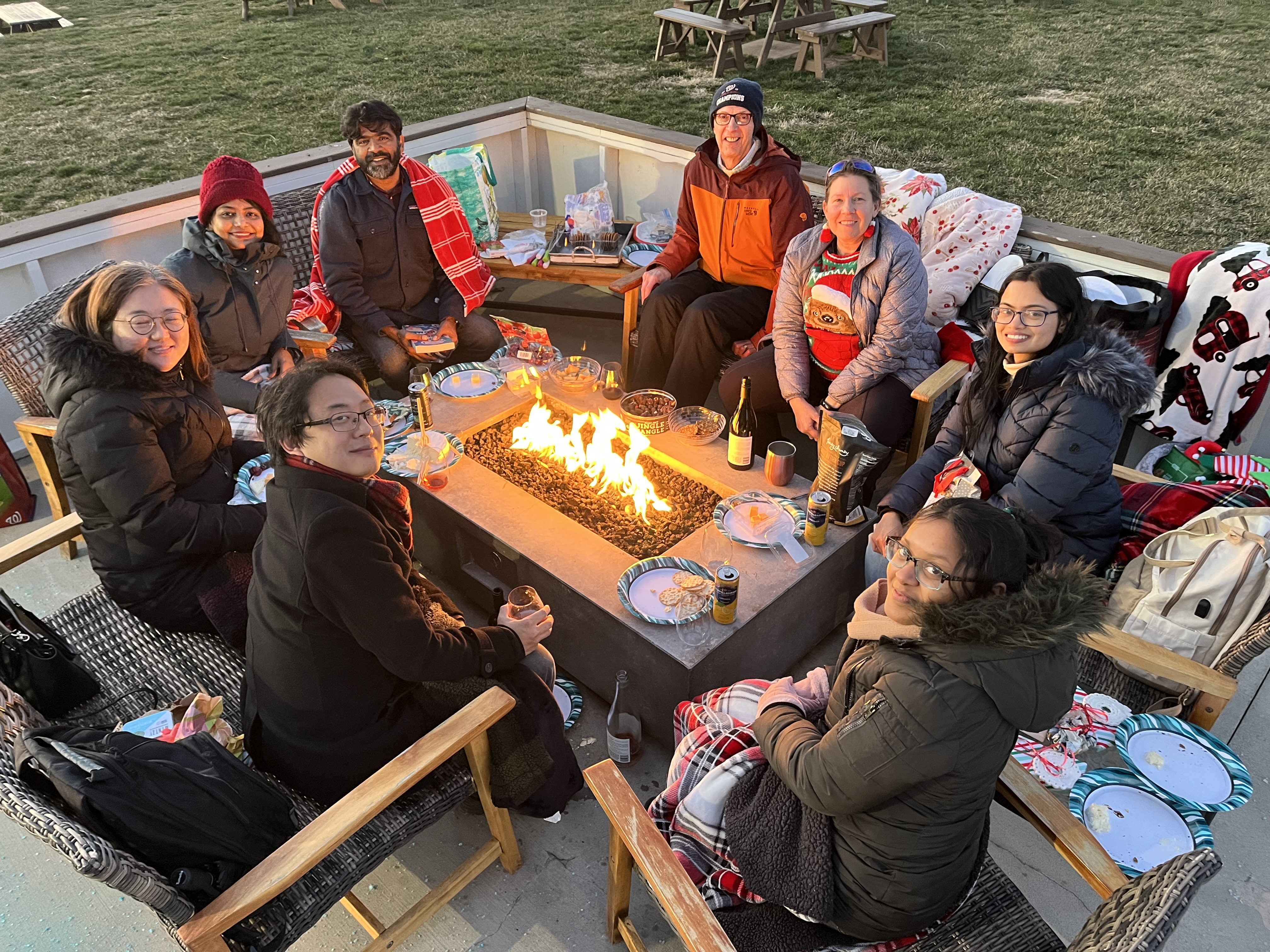 Lab members seated around a firepit outside, celebrating, in 2025. 