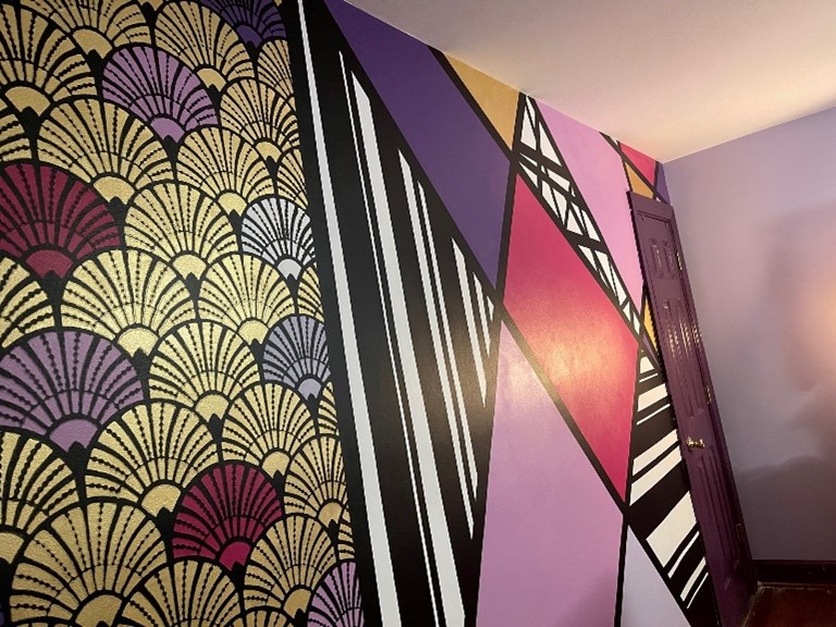 A beautifully painted wall that features intricate geometric patterns painted in thick black lines and an array of complementary colors.