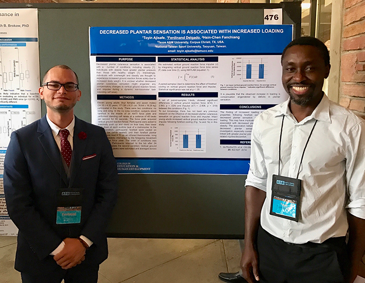 Two people wearing conference badges on lanyards posing in front of a poster they are presenting and smiling.
