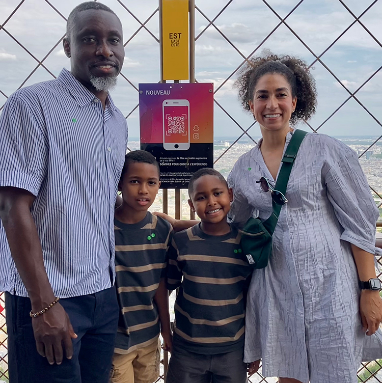 Two parents and their two children posing and smiling for a family photo.