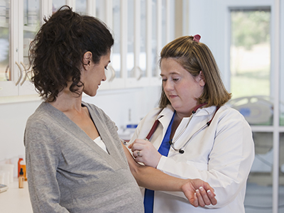 A healthcare provider takes blood from the inner arm of a pregnant woman.