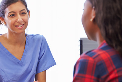 A healthcare provider sitting at a desk having a conversation with a patient.