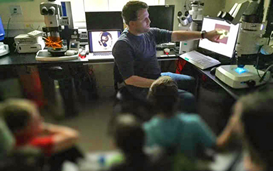 Children gather around a computer.