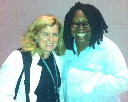 Two women smile for the camera. Dr. Rouault is on the left and wearing her lab coat.