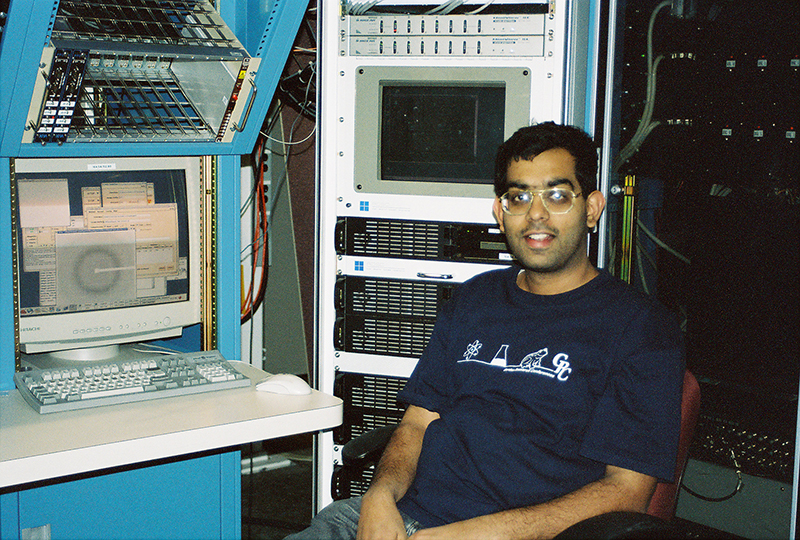 A young man sits at a computer station.