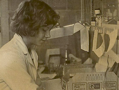 Dr. Bianchi wears a lab coat and looks down at her lab bench.