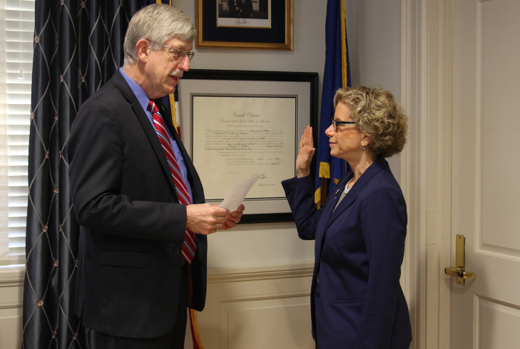 Dr. Collins reads from a sheet of paper while Dr. Bianchi holds up her right hand.