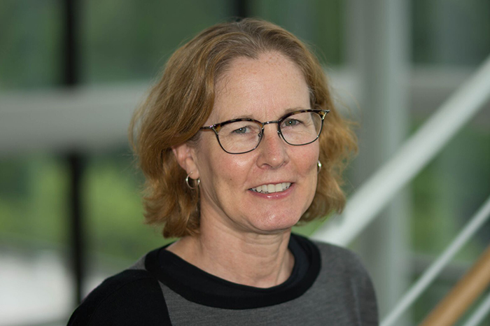 Dr. Dasso is smiling and wearing glasses along a staircase.