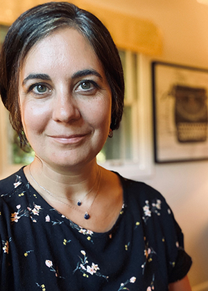 A woman smiles from inside a home.