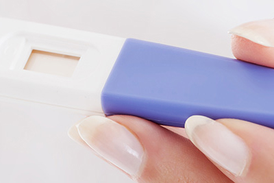 A woman’s hand holding a pregnancy test stick.