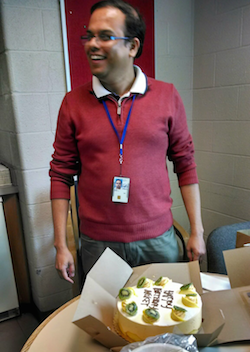 Lab member standing next to cake.