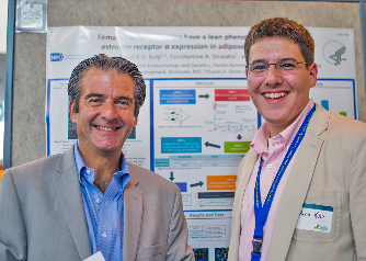 Smiling Dr. Stratakis standing with fellow in front of poster.