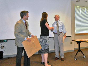 Fellow shaking hands with VIP at graduation ceremony.