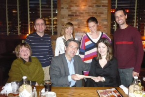 Group of fellows handing award in restaurant.
