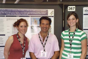 Dr Stratakis with 2 fellows in front of a poster.