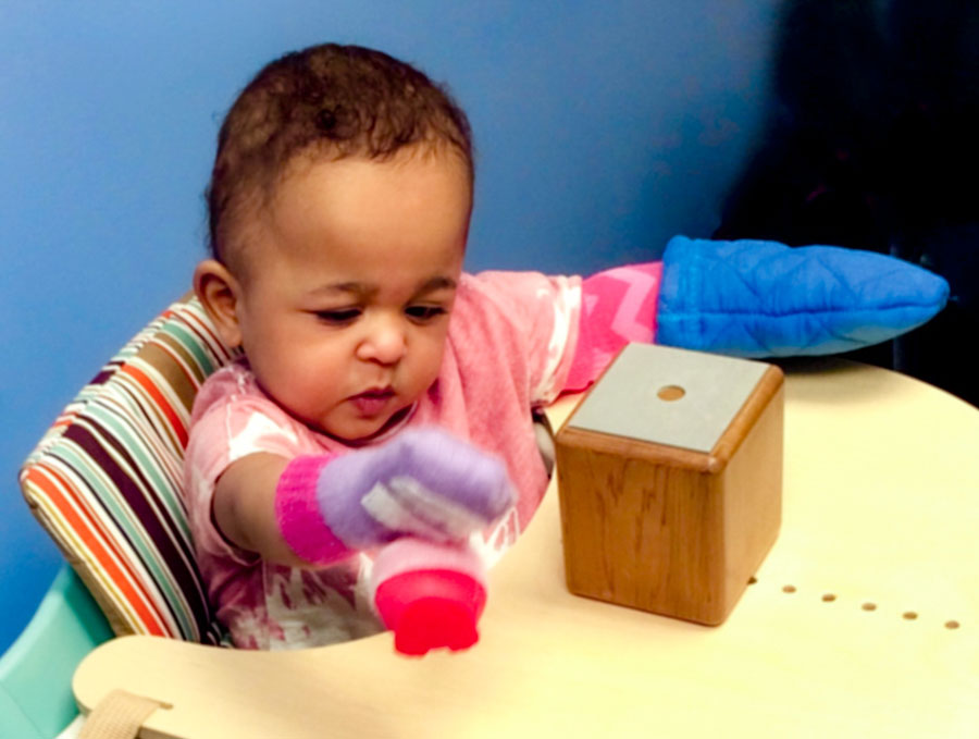 A toddler in a high chair playing with toys.