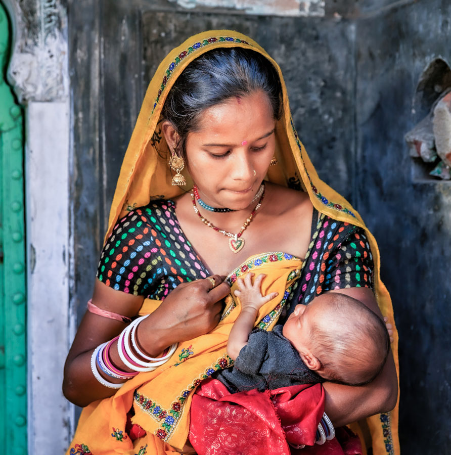 A woman in India wearing traditional dress and breastfeeding a baby.