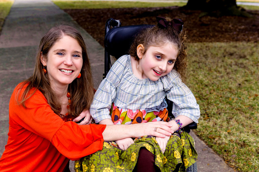 A smiling woman and a young girl with Rett syndrome.