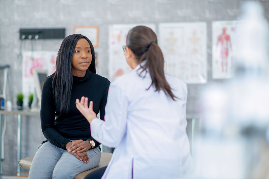 A health professional in a lab coat talking with a patient.