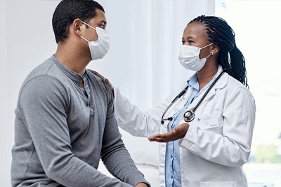 A man speaking with a healthcare provider. Both are wearing masks.