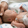 doctor touching head of a premature baby in incubator