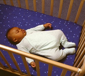 Baby sleeping on back in crib.