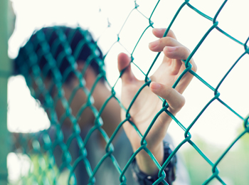 Young man holding onto chain link fence