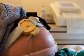 A close-up of a pregnant belly with a fetal monitor attached.