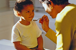 Young boy being spoon-fed medicine